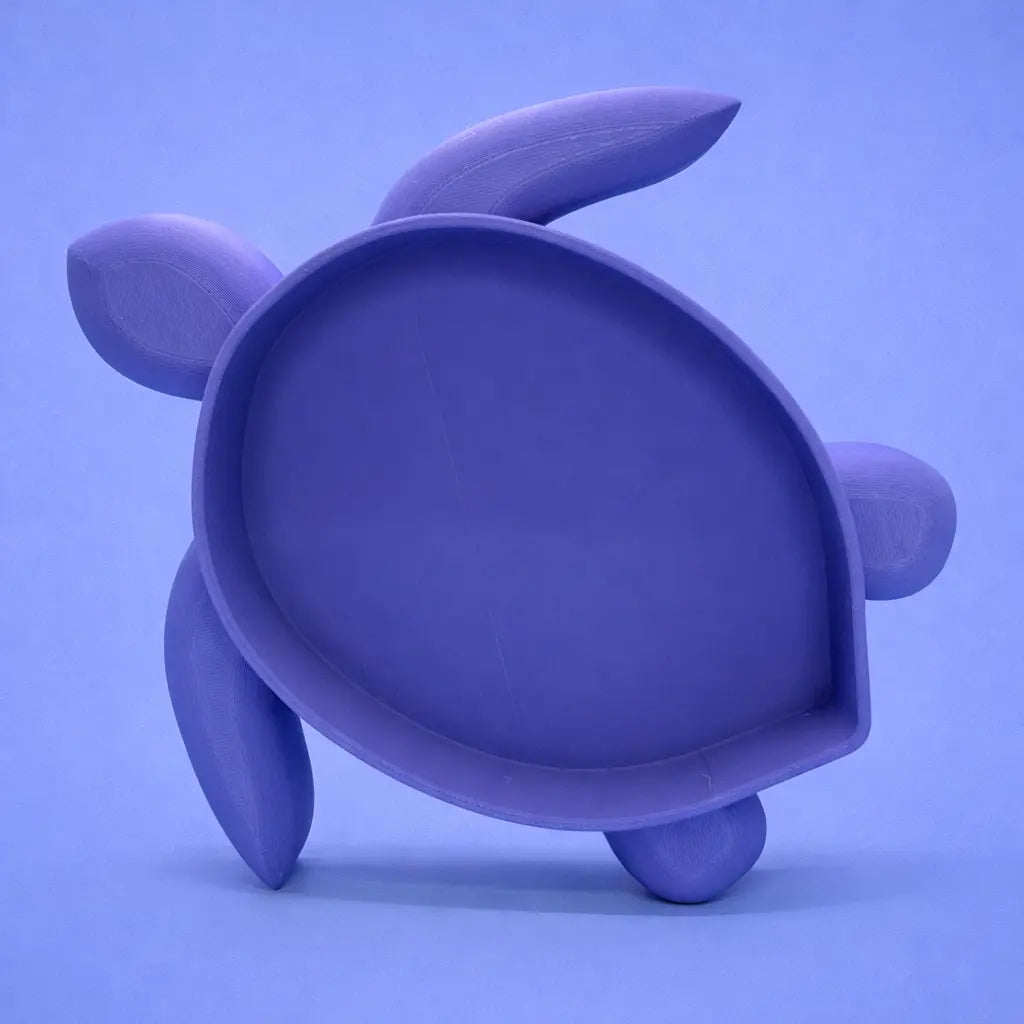 Blue turtle-shaped sand bath with a smooth, shallow basin and rounded flippers, photographed from above on an even light blue background.