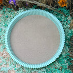Round sand tray with teal rim on a natural background