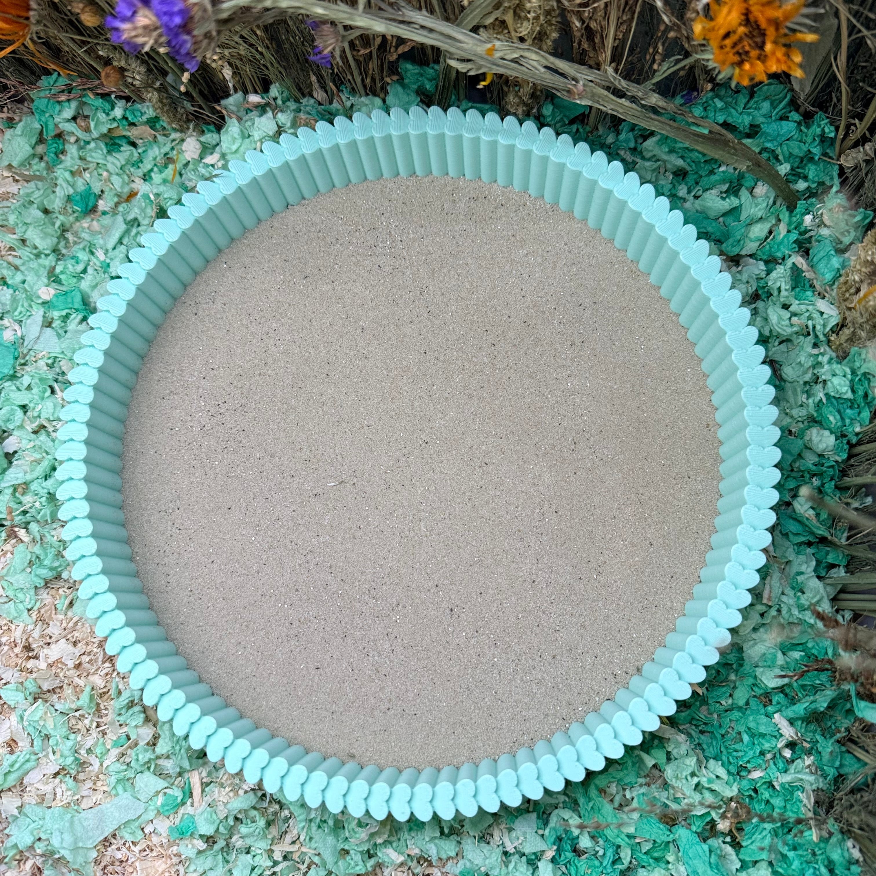 Round sand tray with teal rim on a natural background